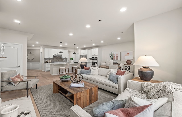 living area featuring a decorative wall, light wood-type flooring, recessed lighting, and wainscoting