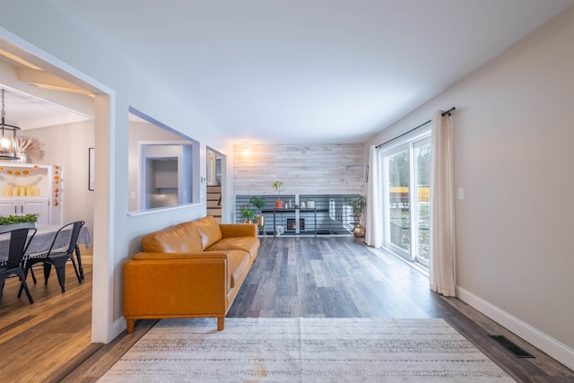 living room with wood-type flooring, wooden walls, and an inviting chandelier