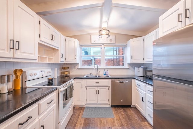 kitchen with lofted ceiling, appliances with stainless steel finishes, sink, and white cabinets