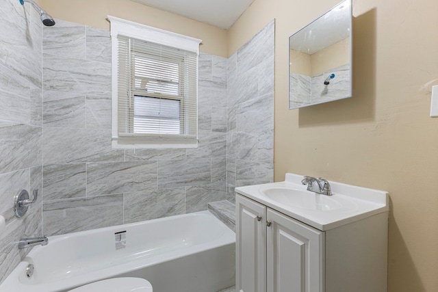 full bathroom featuring vanity, tiled shower / bath combo, and toilet