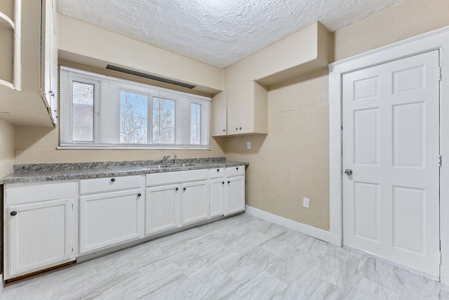 clothes washing area with sink and a textured ceiling