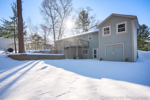 snow covered property featuring a wooden deck and a garage