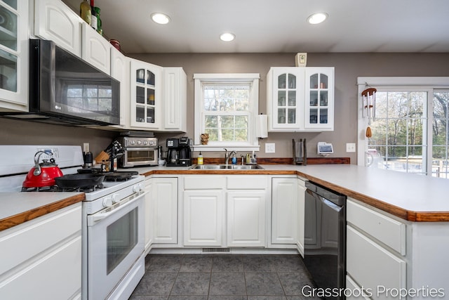 kitchen with white cabinets, kitchen peninsula, sink, and black appliances