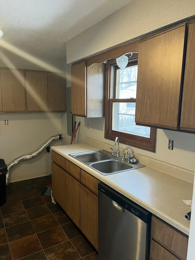 kitchen with stainless steel dishwasher, sink, and a textured ceiling