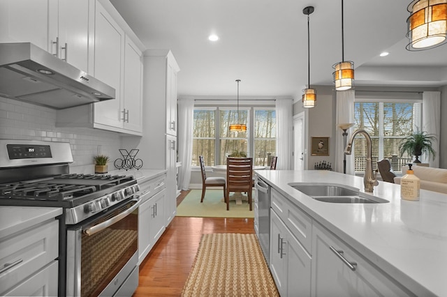 kitchen featuring appliances with stainless steel finishes, sink, pendant lighting, and white cabinets