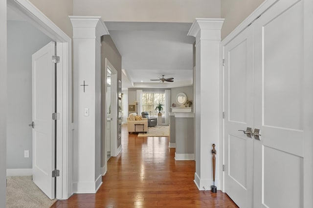 hallway featuring wood-type flooring and ornate columns