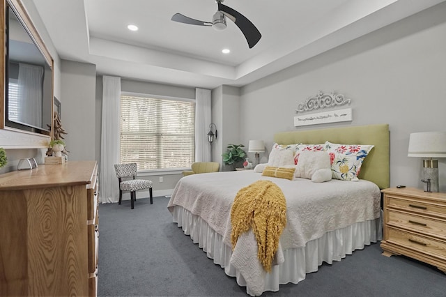 carpeted bedroom with a raised ceiling and ceiling fan