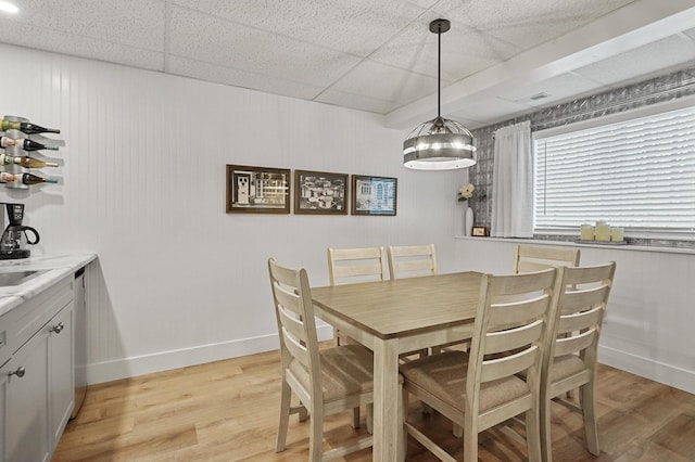 dining area with a drop ceiling and light hardwood / wood-style floors