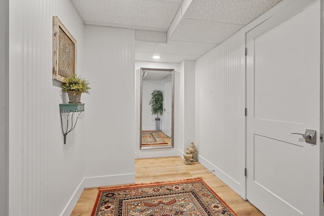 corridor with wood-type flooring and a paneled ceiling