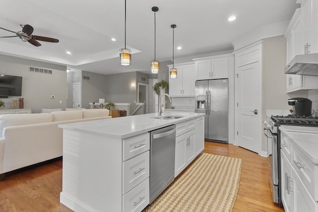 kitchen with sink, appliances with stainless steel finishes, white cabinetry, a kitchen island with sink, and decorative light fixtures