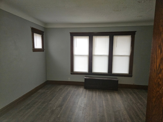 unfurnished room with dark wood-type flooring, radiator, and a textured ceiling