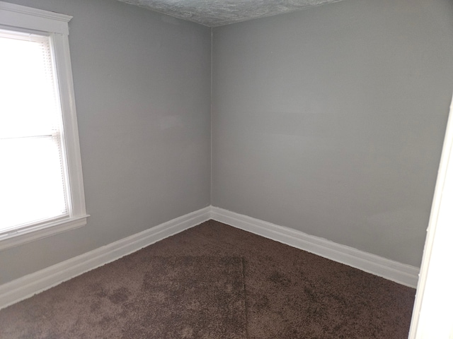 carpeted empty room featuring a textured ceiling