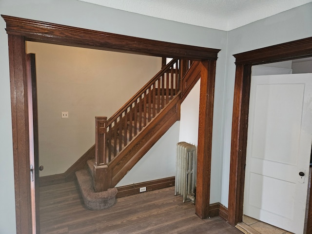 staircase featuring hardwood / wood-style flooring, radiator, and a textured ceiling