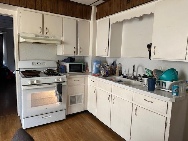 kitchen with sink, dark hardwood / wood-style flooring, white gas range oven, and white cabinets