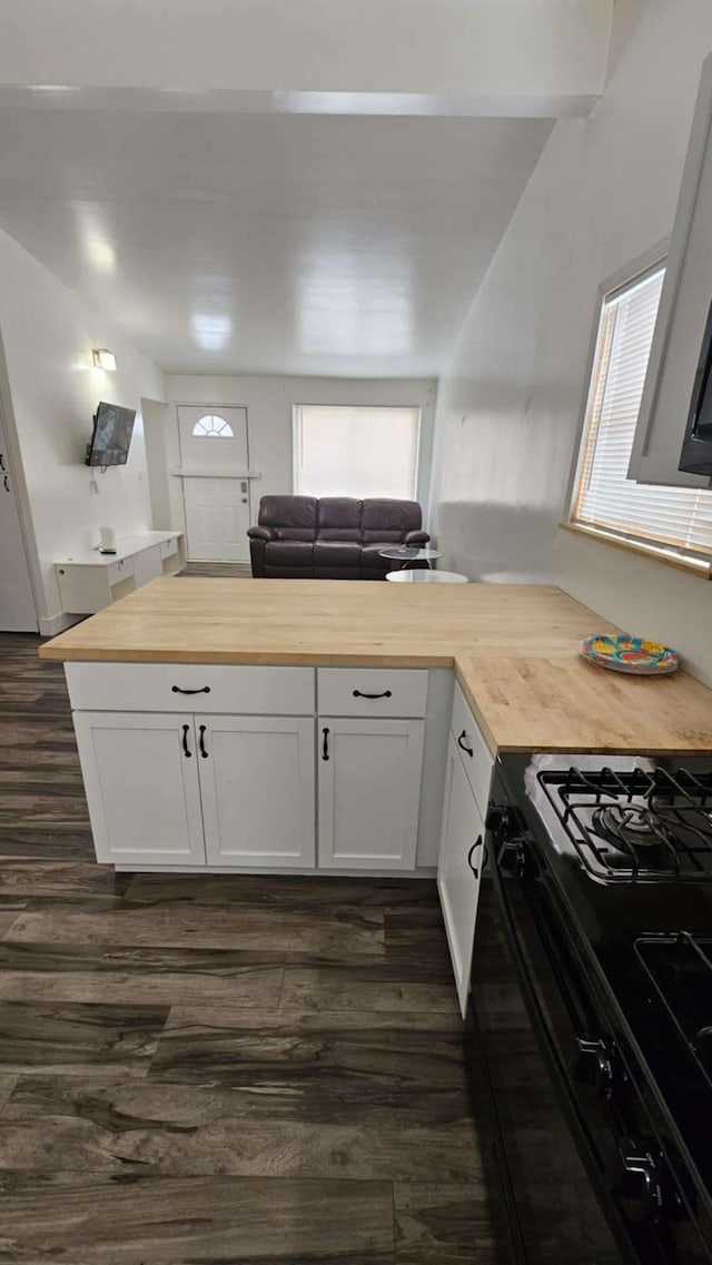 kitchen featuring white cabinetry, butcher block countertops, dark hardwood / wood-style floors, and black gas stove