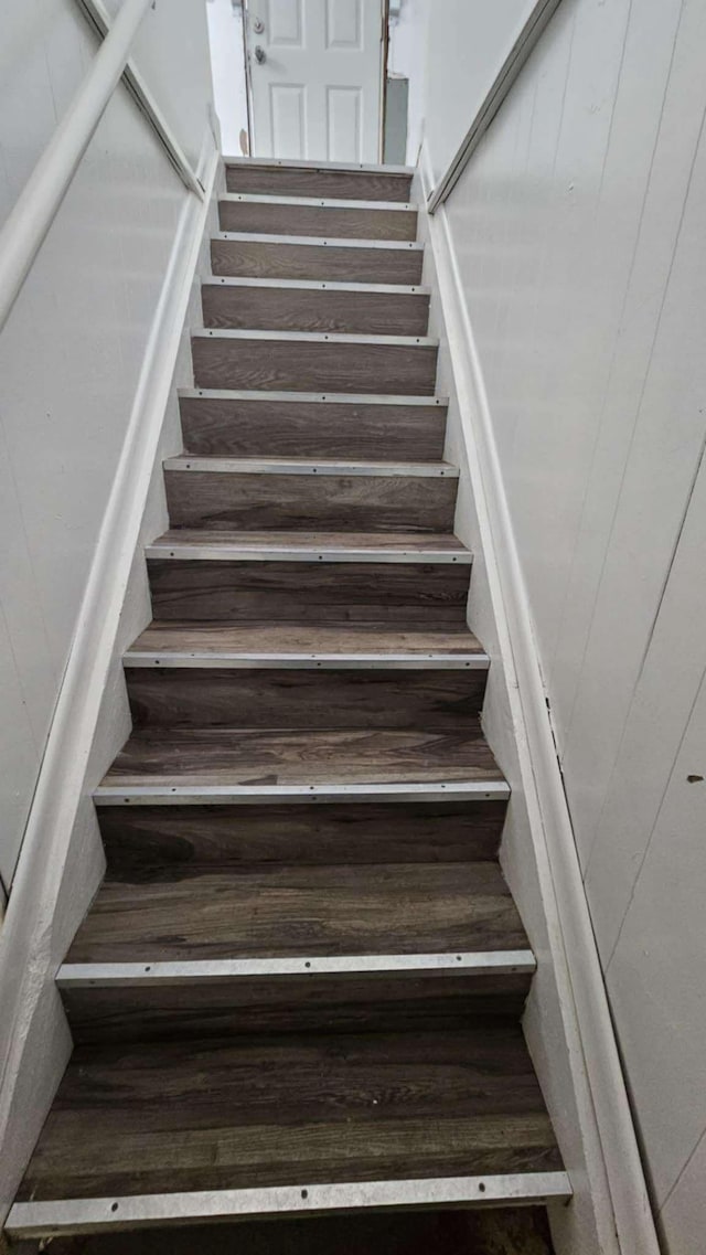 stairway featuring wooden walls