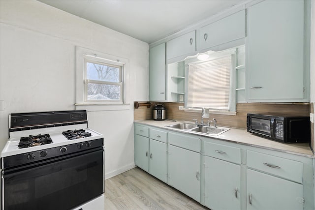 kitchen with sink, decorative backsplash, white range with gas stovetop, and light wood-type flooring