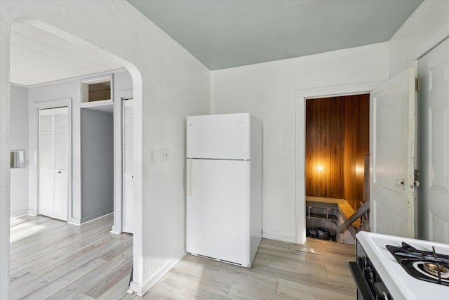 kitchen with gas range, light wood-type flooring, and white fridge