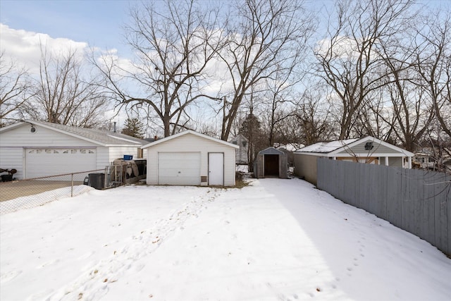 snowy yard featuring a garage and a shed