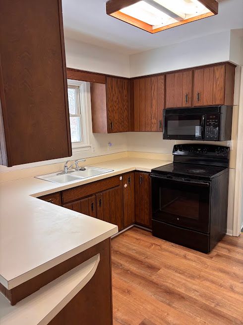 kitchen featuring sink, black appliances, kitchen peninsula, and light wood-type flooring