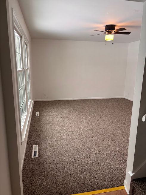 empty room with ceiling fan and carpet