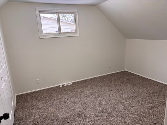 bonus room featuring vaulted ceiling and dark colored carpet