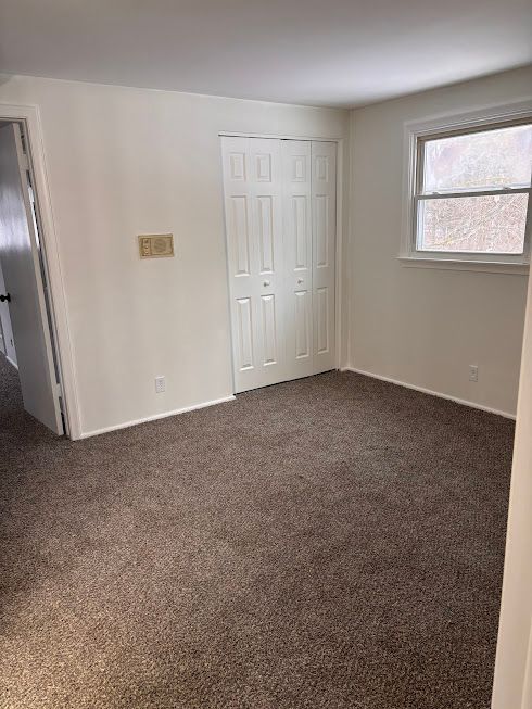 unfurnished bedroom featuring dark colored carpet and a closet