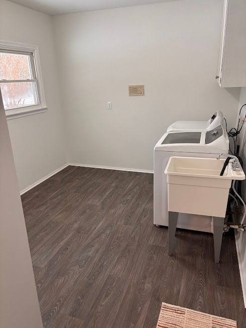 laundry room featuring washing machine and dryer, dark hardwood / wood-style floors, and sink