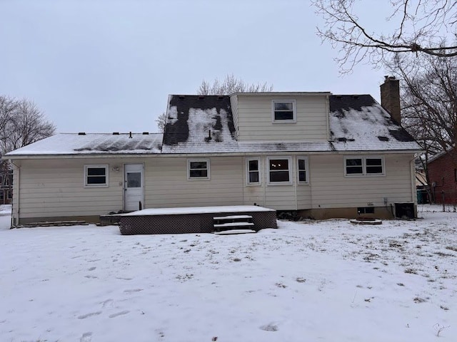 snow covered rear of property with central AC and a wooden deck