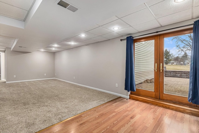 empty room featuring a paneled ceiling, hardwood / wood-style floors, and french doors