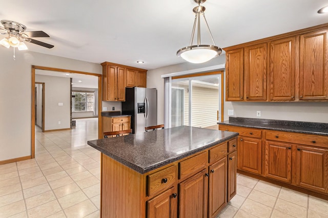 kitchen with light tile patterned floors, stainless steel fridge, ceiling fan, a center island, and decorative light fixtures