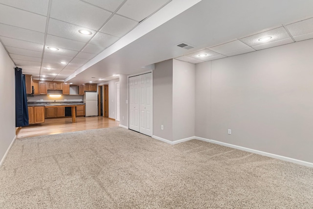 unfurnished living room featuring a paneled ceiling and light colored carpet