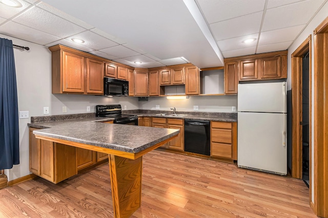 kitchen featuring sink, light hardwood / wood-style flooring, kitchen peninsula, and black appliances