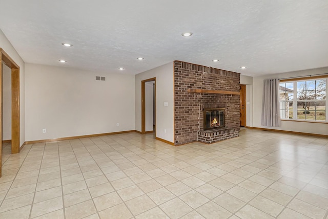 unfurnished living room featuring a brick fireplace, a textured ceiling, and light tile patterned floors