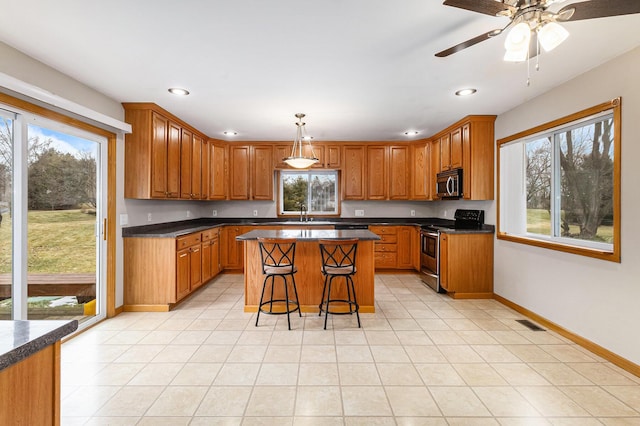 kitchen featuring a kitchen island, pendant lighting, a kitchen breakfast bar, light tile patterned floors, and stainless steel appliances