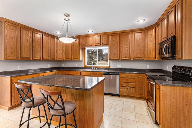 kitchen featuring a kitchen bar, sink, appliances with stainless steel finishes, a kitchen island, and pendant lighting