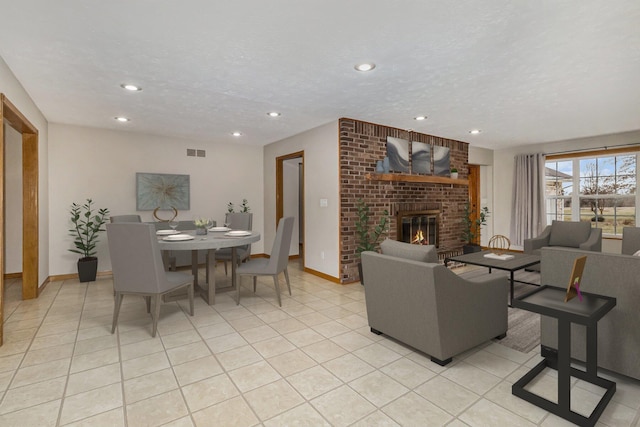 living room featuring light tile patterned floors, a textured ceiling, and a brick fireplace