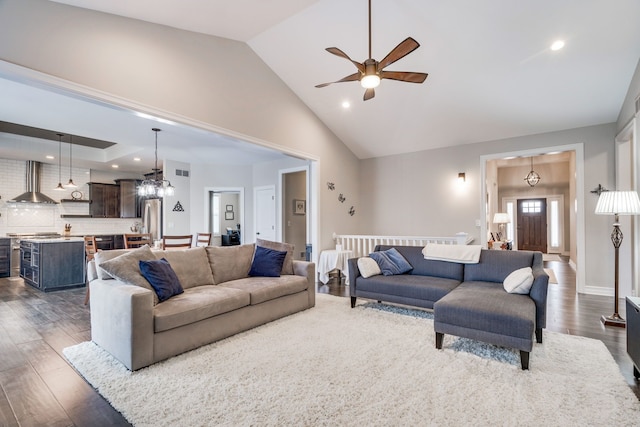 living room with high vaulted ceiling, ceiling fan with notable chandelier, and dark hardwood / wood-style flooring