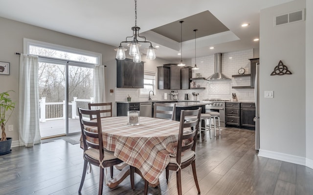 dining area featuring dark hardwood / wood-style flooring, sink, and a tray ceiling