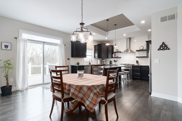 dining space with dark hardwood / wood-style flooring and a tray ceiling