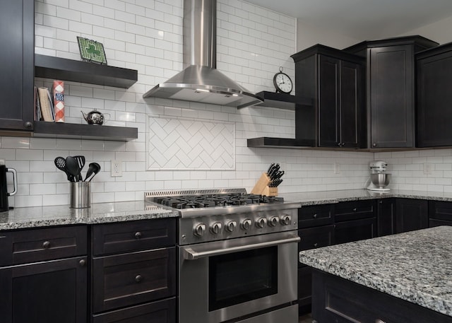 kitchen featuring light stone countertops, high end stainless steel range, backsplash, and wall chimney exhaust hood