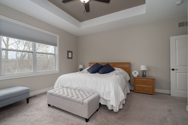 bedroom with light carpet, a tray ceiling, and ceiling fan