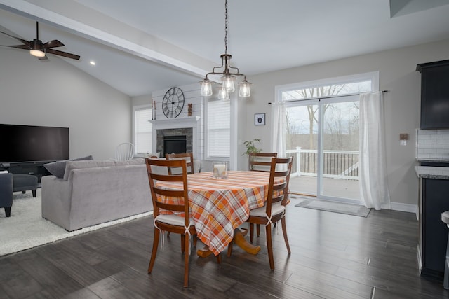 dining area featuring dark hardwood / wood-style floors, ceiling fan, a fireplace, and vaulted ceiling