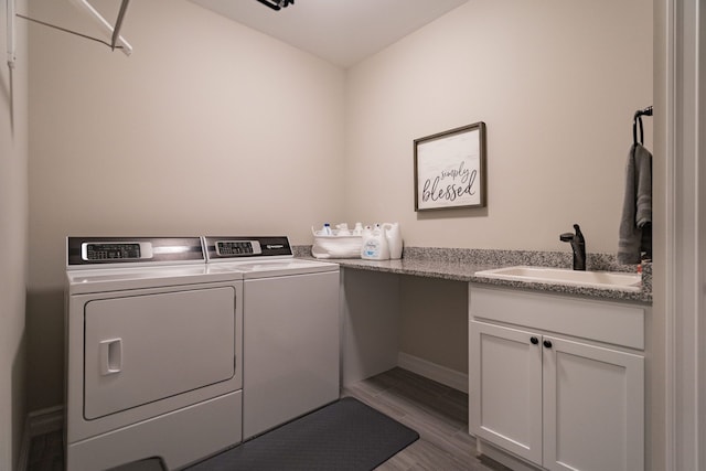 laundry room featuring cabinets, wood-type flooring, sink, and washer and clothes dryer