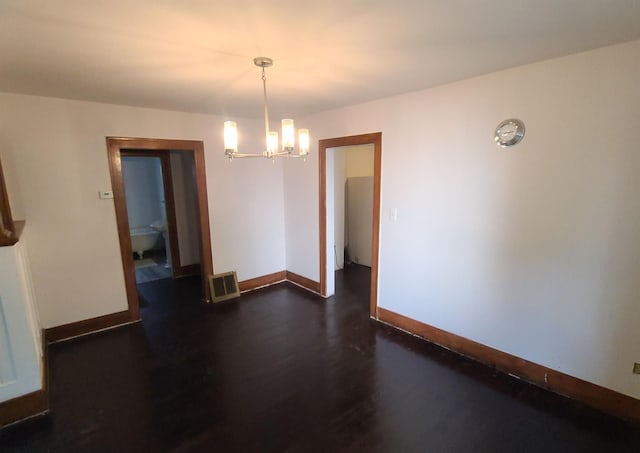 spare room with an inviting chandelier and dark hardwood / wood-style flooring