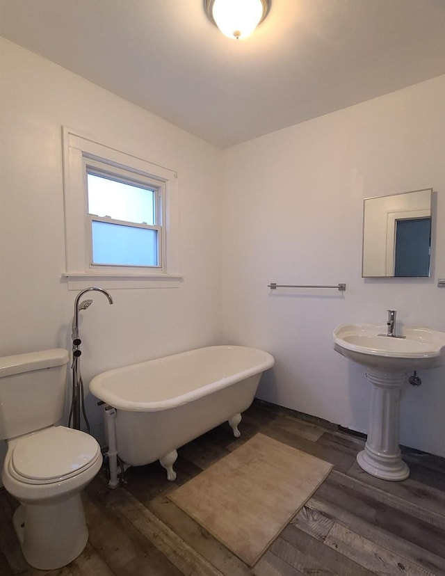 bathroom featuring wood-type flooring, a bath, and toilet