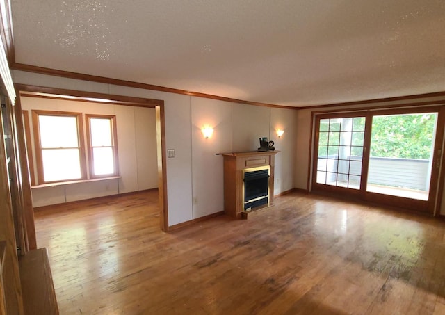 unfurnished living room with hardwood / wood-style flooring, ornamental molding, and plenty of natural light