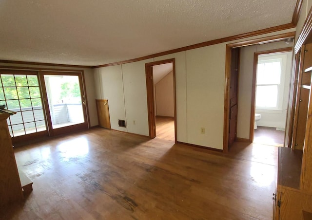 empty room with crown molding, light hardwood / wood-style flooring, and a textured ceiling