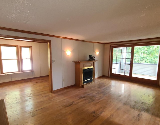 unfurnished living room with ornamental molding and hardwood / wood-style floors