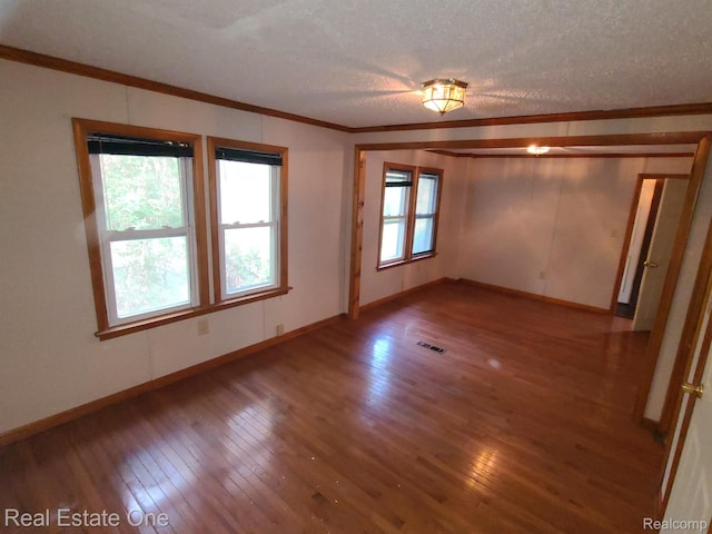 empty room with ornamental molding, wood-type flooring, and a textured ceiling